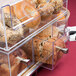 A Cal-Mil clear acrylic container with bread, bagels, and muffins.