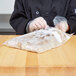 A person wearing gloves holding a LK Packaging plastic bag of food.