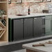 A black, three-door underbar height back bar refrigerator designed for commercial use.