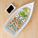 A plate of sushi on a wooden surface with a white bowl of black liquid.