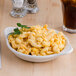 A Tuxton eggshell round shirred egg dish filled with macaroni and cheese on a table.