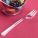 A clear plastic Fineline Tiny Tines tasting fork in a bowl of fruit.