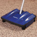 A blue and black Carlisle Duo-Sweeper floor sweeper on carpet.