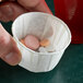 A hand holding a Genpak paper souffle cup filled with pills.