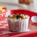 A red tray with a Genpak Harvest white souffle cup of food.