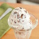 A scoop of Mini Milk Chocolate Peanut Butter Cups on ice cream in a glass cup.