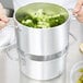 A person using a Vollrath rice and vegetable steamer to cook broccoli.