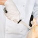 A person in white gloves using a Dexter-Russell V-Lo fillet knife to cut a chicken.