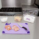 A San Jamar purple allergen-free cutting board with a knife and raw meat on it.