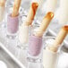 A tray of dessert shot glasses filled with cream, chocolate, and pink smoothies.