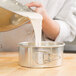 a person pouring dough into a bowl