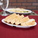 A white Thunder Group Nustone melamine oval platter with sliced bread on it.