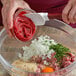 A person mixing Furmano's tomato paste in a bowl.