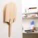 An American Metalcraft wooden pizza peel rack with two hooks on a wall.