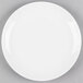 A Tuxton bright white china plate with a white rim on a gray surface.