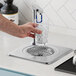 A person using a Delfield self-contained water station to fill a glass with ice water.