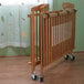 A L.A. Baby natural wood folding crib on wheels.