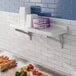 A white Cambro Camshelving wall shelf holding purple boxes with black text.