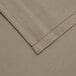 A close-up of a beige fabric table cover with a white hem.