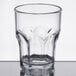 A Carlisle clear plastic tumbler with a rim on a table.