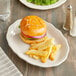 An Acopa ivory stoneware platter with a hamburger and fries.