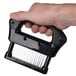 A hand holding a black Chef Master 16 blade meat tenderizer with a white background.