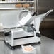 A Globe G12A meat slicer on a counter with thin slices of meat.
