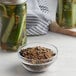 A jar of pickles with a bowl of Regal Old Fashion Pickling Spice on a counter.