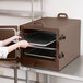 A person holding a Cambro dark brown tray in a professional kitchen.