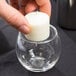 A hand holding a candle in a Libbey glass votive candle holder.