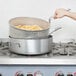 A person using a Vollrath Wear-Ever fry pot to fry french fries.