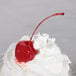 A close up of a Regal Maraschino Cherry on top of whipped cream.