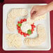 A hand holding a white square stoneware platter with cheese, crackers, and tomatoes.