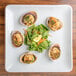 A white square stoneware platter with a salad and clams on it.