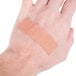 A person's hand with a Medique woven bandage strip on it.