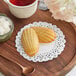 A wooden tray with 5" Normandy lace doilies holding cookies and a cup of tea on a table.