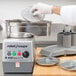 A gloved hand uses a Robot Coupe 1/4" grating/shredding disc in a machine.
