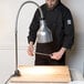 A man in a black chef's coat using a Cres Cor portable carving station to cut a wooden board.