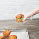 A hand holding a muffin over a Chicago Metallic bakery display tray.