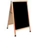 An Aarco oak A-frame sign board with a black marker board.