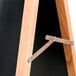 An Aarco oak A-frame sign board with a black marker board on a metal bracket.