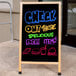 An Aarco oak A-frame chalkboard with colorful writing.