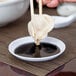 A person using chopsticks to pick up sauce from a bowl.