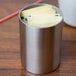 A silver Tablecraft stainless steel sugar caddy with yellow papers inside.