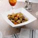A white 10 Strawberry Street Whittier square porcelain rim bowl filled with food.