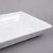 An American Metalcraft white rectangular stoneware platter on a gray surface.