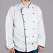 A man wearing a white Chef Revival chef coat with black piping.