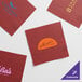 A red Choice Burgundy 2-ply napkin with a logo in gold.