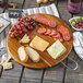 A Tablecraft acacia wood round display board with food on it.