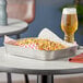 A Tablecraft stainless steel rectangular platter holding corn on the cob on a table.